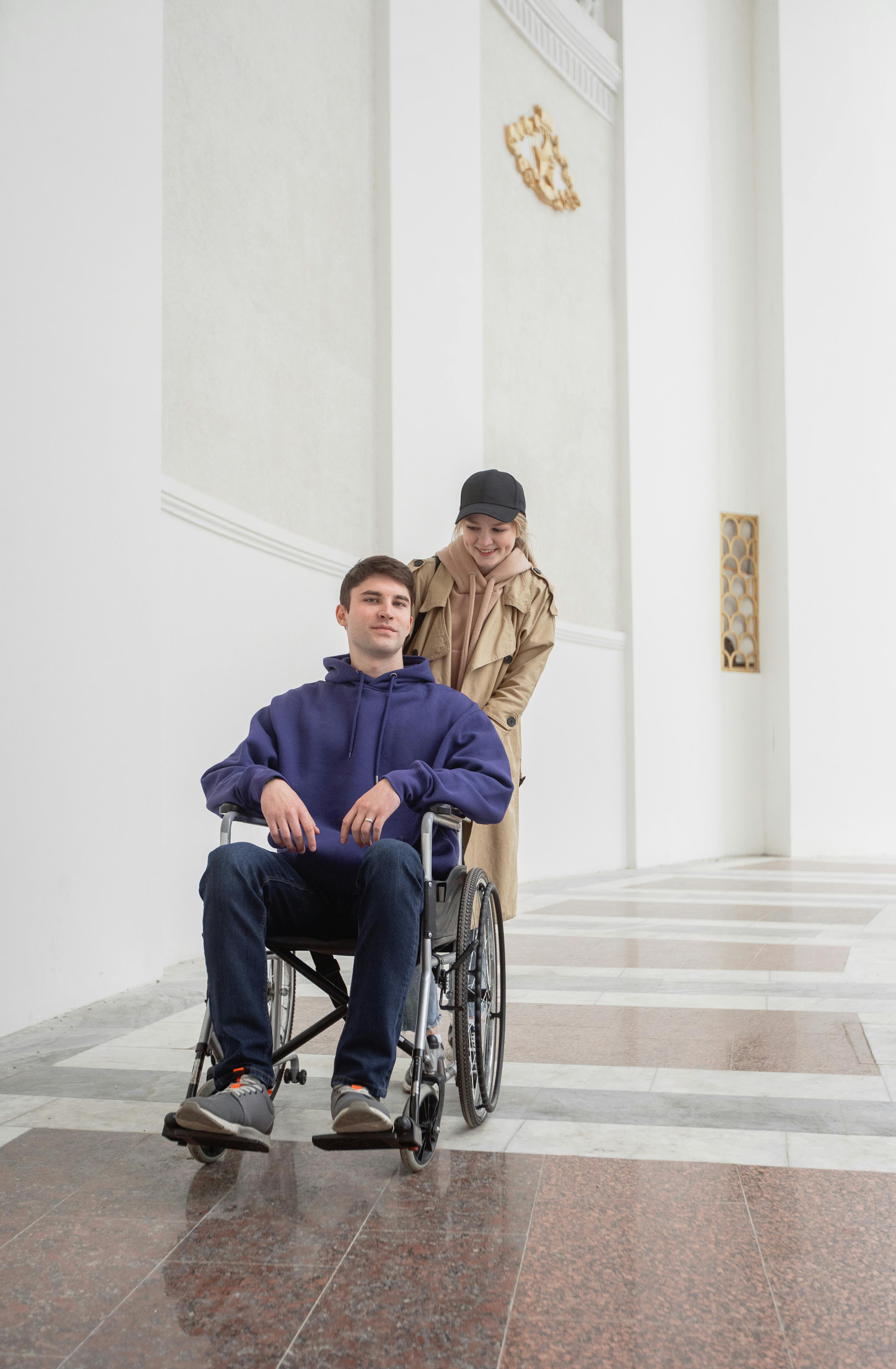 Woman Pushing A Man Sitting On A Wheelchair · Free Stock Photo