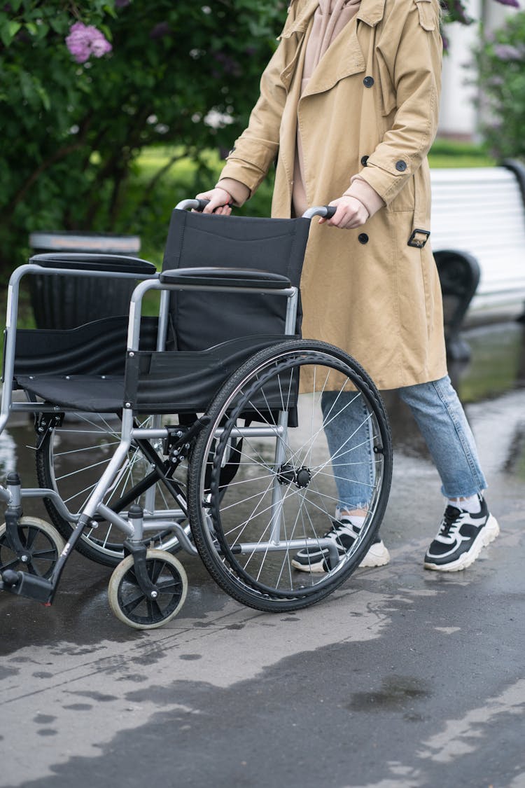 A Person In Brown Coat Pushing A Wheelchair