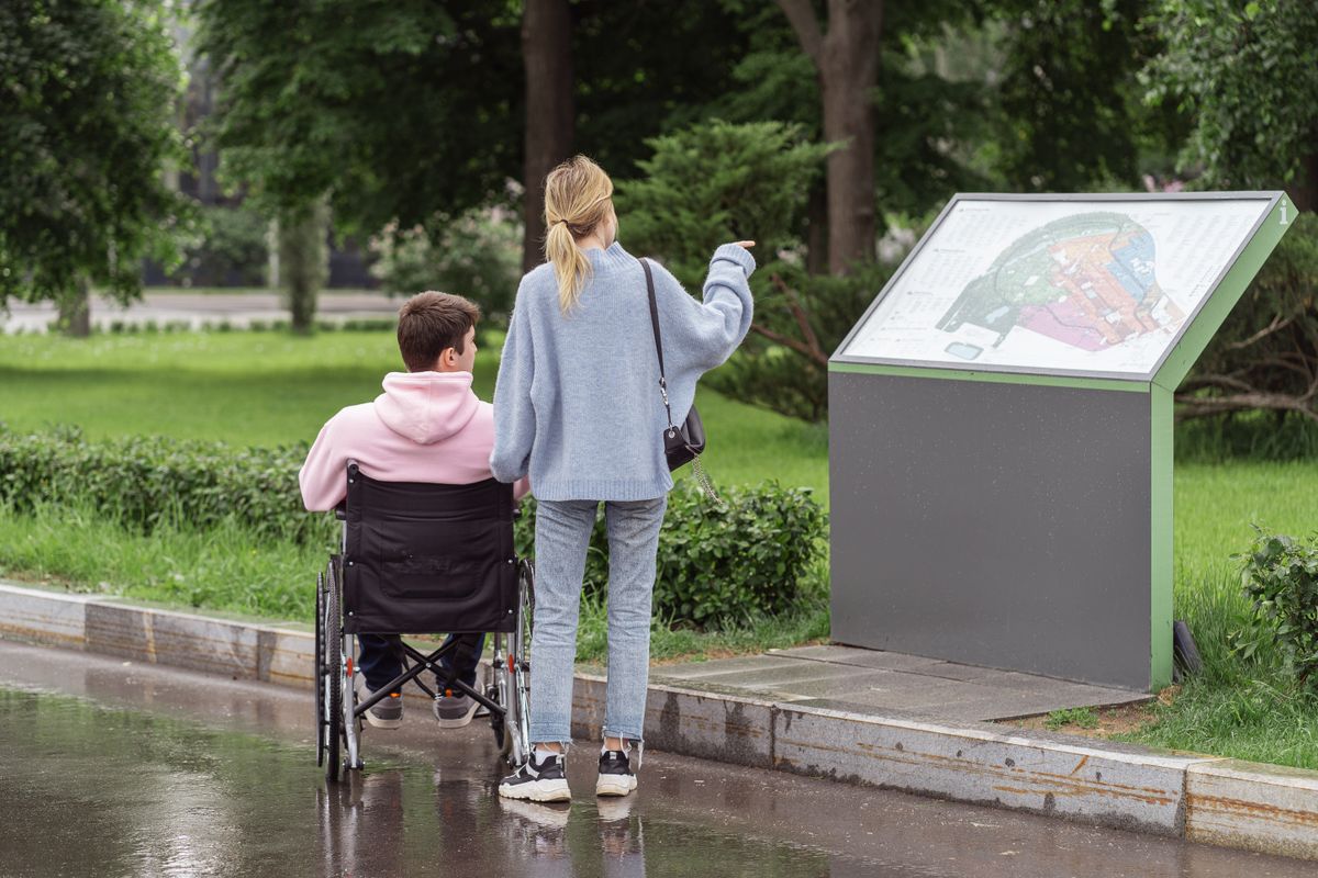 Two people checking a park map together, one using a wheelchair