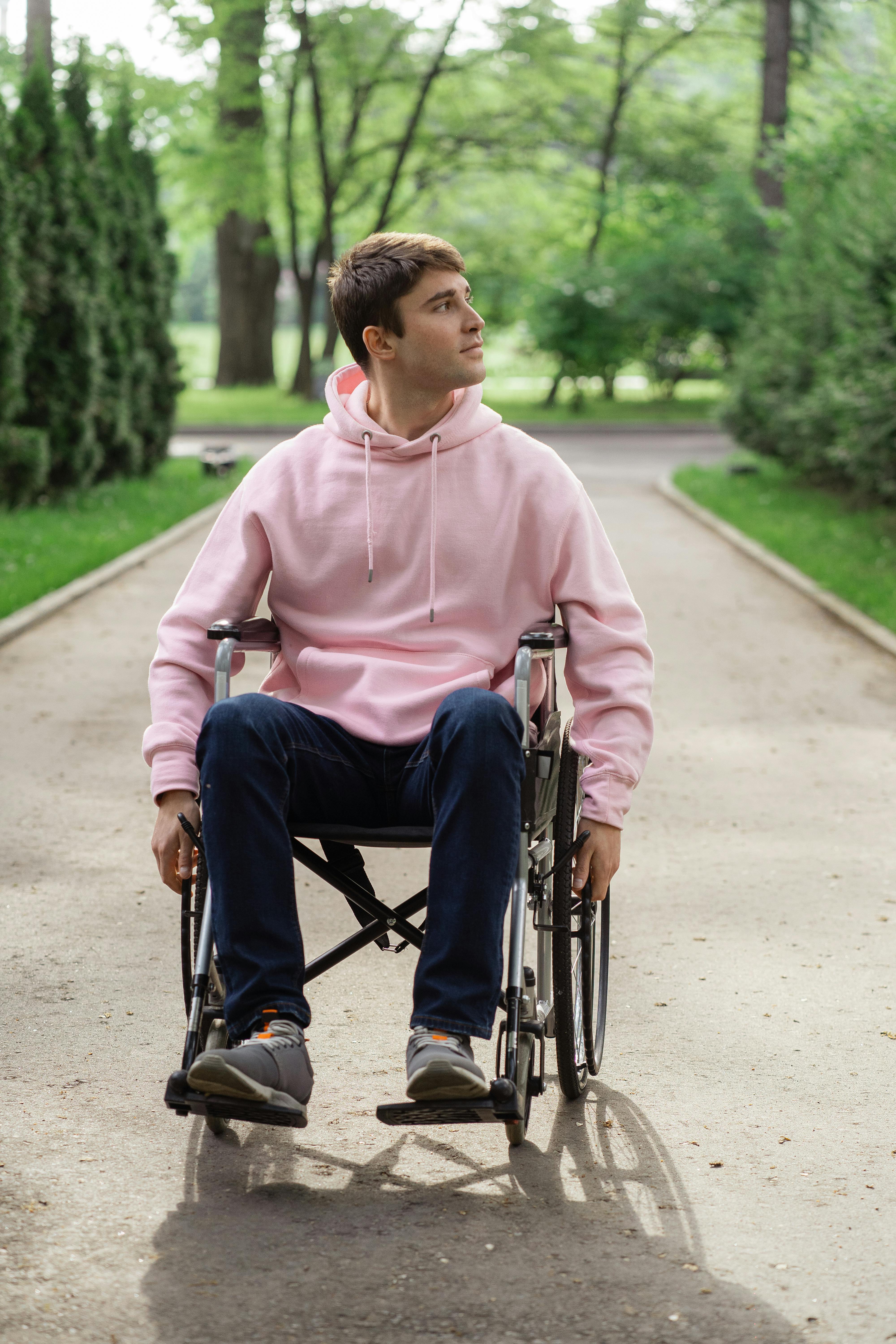 man in pink hoodie sitting on the wheelchair