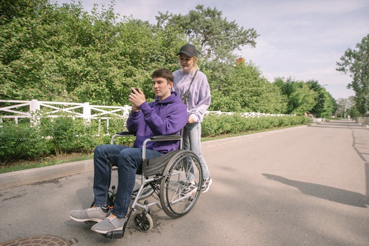 Woman Pushing The Wheelchair With A Man