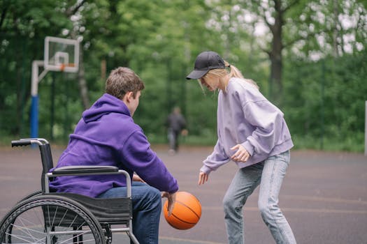 A man in wheelchair playing basketball with a woman in a park setting.