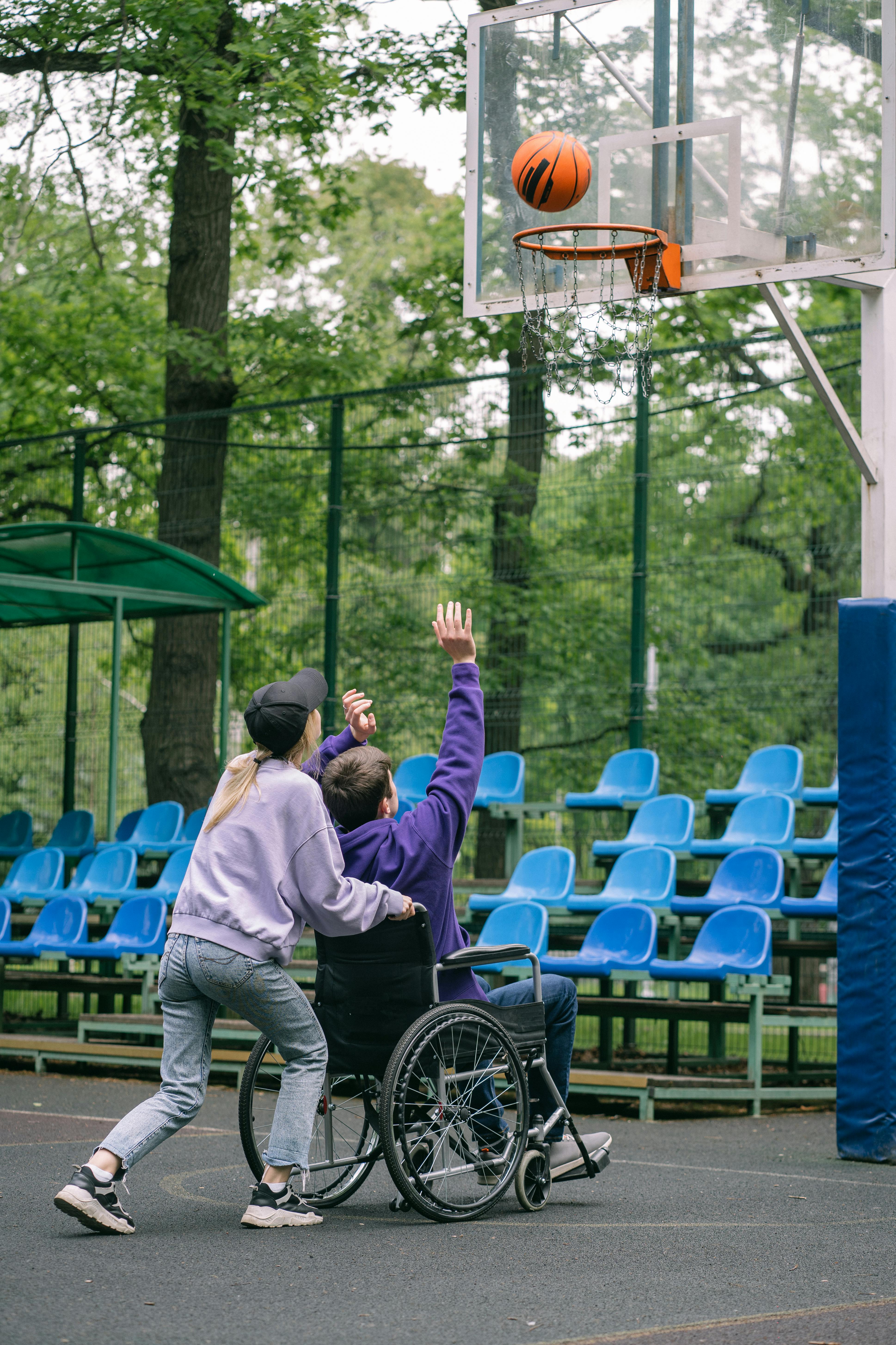 a man sitting on the wheelchair shooting a ball