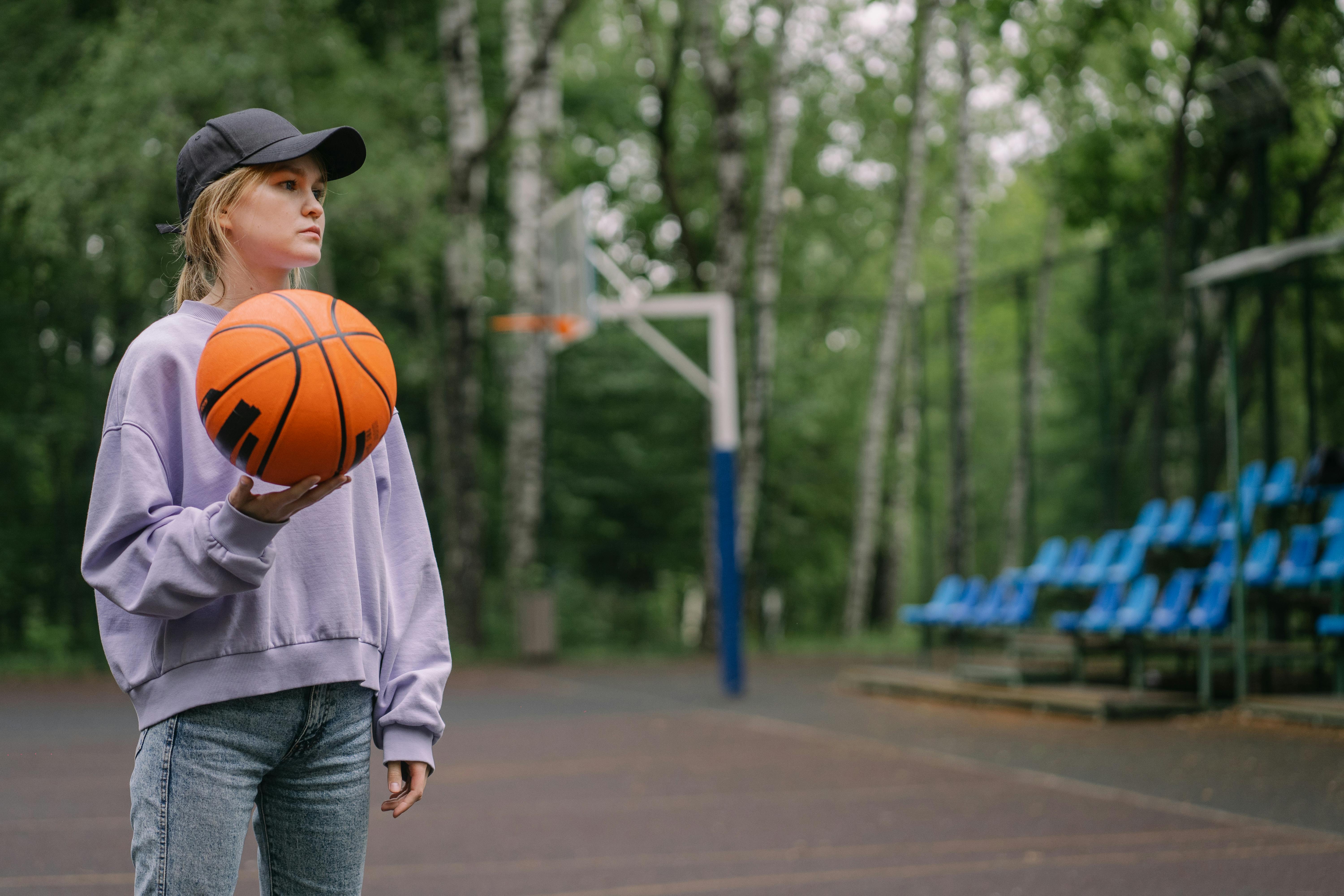 A Woman Wearing Black Cap While Holding Ball · Free Stock Photo