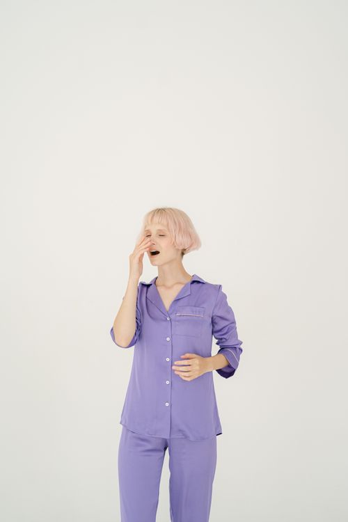 Free A woman in lavender pajamas yawning isolated on a white background. Ideal for sleep or lifestyle themes. Stock Photo