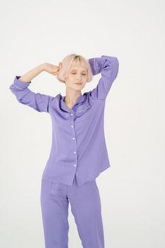 A serene woman in lavender pajamas poses with closed eyes, exuding tranquility and comfort.