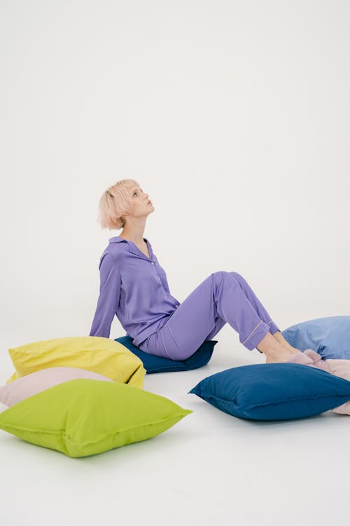 Free Woman in Purple Sleepwear Sitting on Throw Pillow Stock Photo