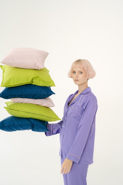 Woman in Purple Sleepwear Holding Throw Pillows