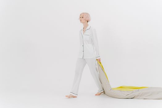 Woman in White Sleepwear Dragging a Comforter