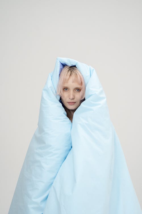 A Woman Wrapped Around with Blanket while Seriously Looking at the Camera