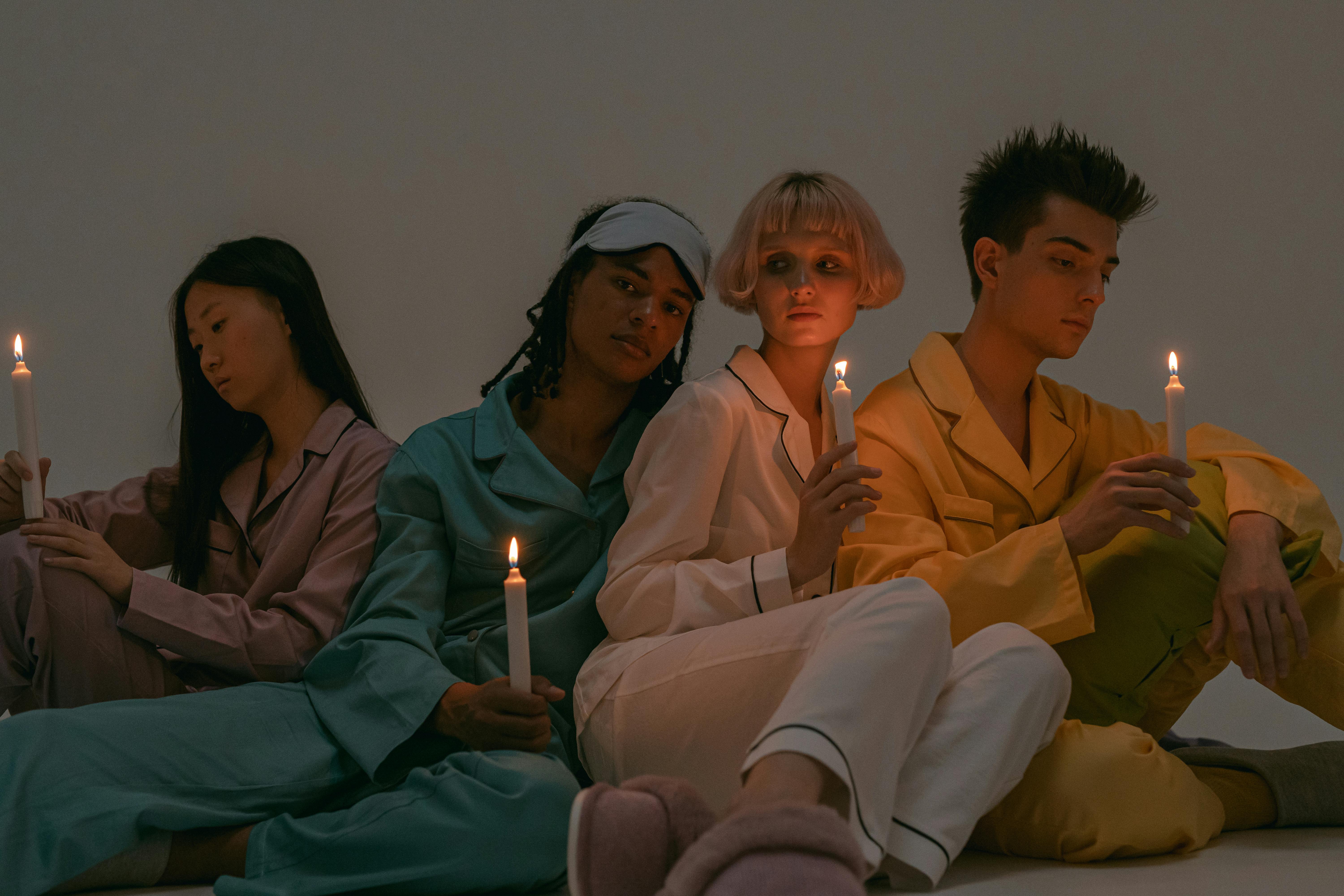 A diverse group in pajamas holding candles, creating an intimate and reflective mood.