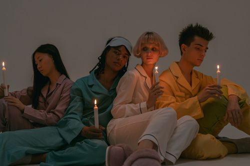 Free A diverse group in pajamas holding candles, creating an intimate and reflective mood. Stock Photo