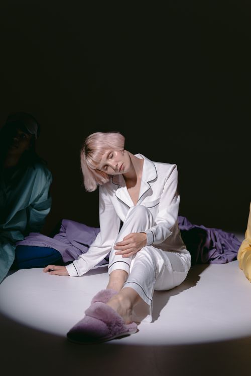 Free A serene moment with a woman relaxing in modern pajamas under dramatic lighting. Stock Photo