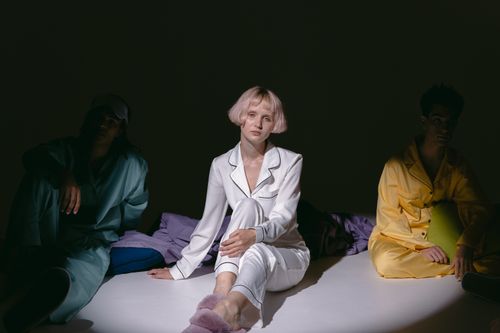 Free A stylish group in colorful sleepwear sitting in a low-lit studio, showcasing modern loungewear fashion. Stock Photo
