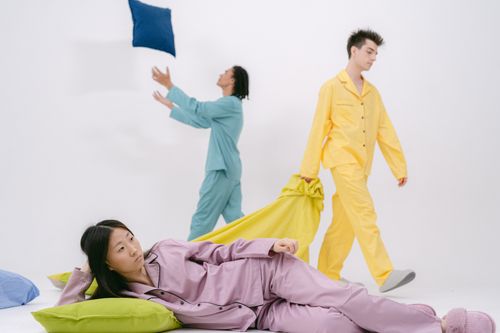 Free Young adults in colorful pajamas having fun in a room with pillows on a white background. Stock Photo