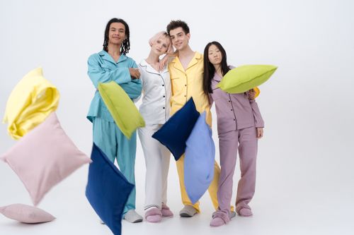 Free Group of adults in pajamas having pillow fight fun indoors, showcasing vibrant colors. Stock Photo