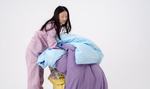 Free A Woman in Purple Pajamas Holding Blankets Stock Photo