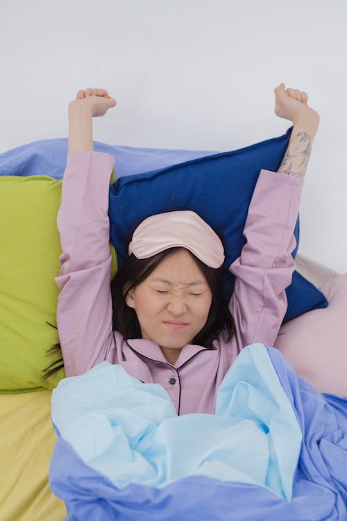 Free A Woman Stretching Her Arms while Lying on the Bed Stock Photo