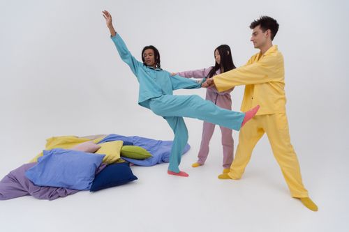 Free Three diverse people in colorful pajamas playfully standing with pillows against a white background. Stock Photo