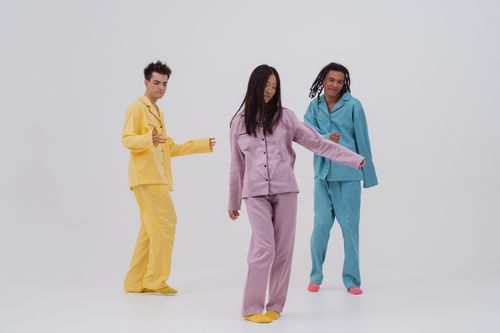 Free Three young adults wearing colorful pajamas dance joyfully on a white background. Stock Photo