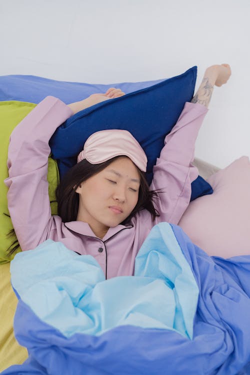 Free A Woman in Pink Sleepwear and Eye Mask Sleeping on the Bed Stock Photo