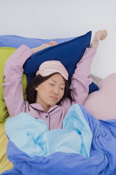 Woman in cozy sleepwear stretching on colorful bed with a sleep mask on. Perfect restful morning scene.