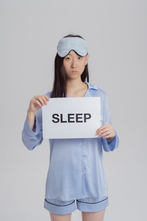 Free A Woman in Blue Pajama Holding a White Paper with Message Stock Photo