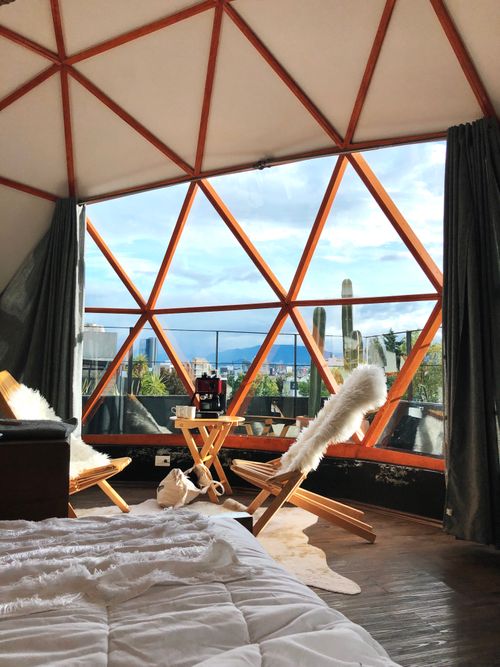 Free Modern geodesic dome interior with wooden furniture and scenic window view, offering a cozy atmosphere. Stock Photo