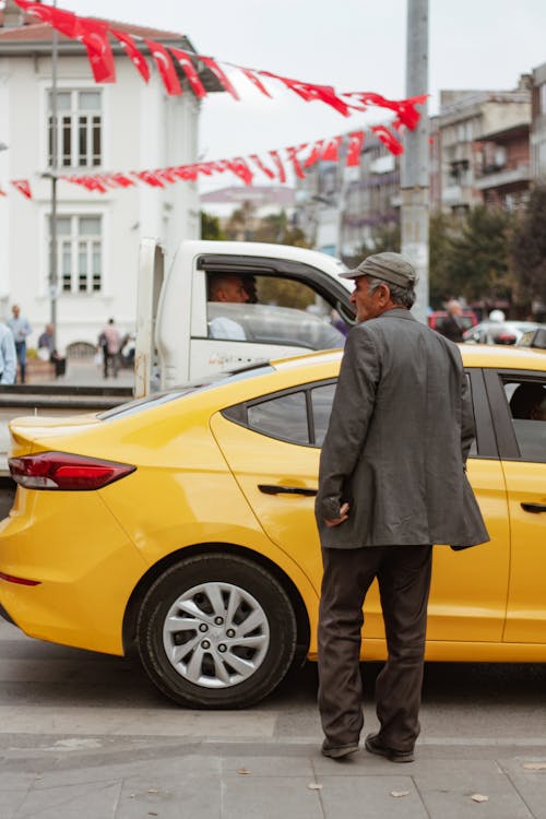 Ethnic citizen on pavement against taxi cab and buildings