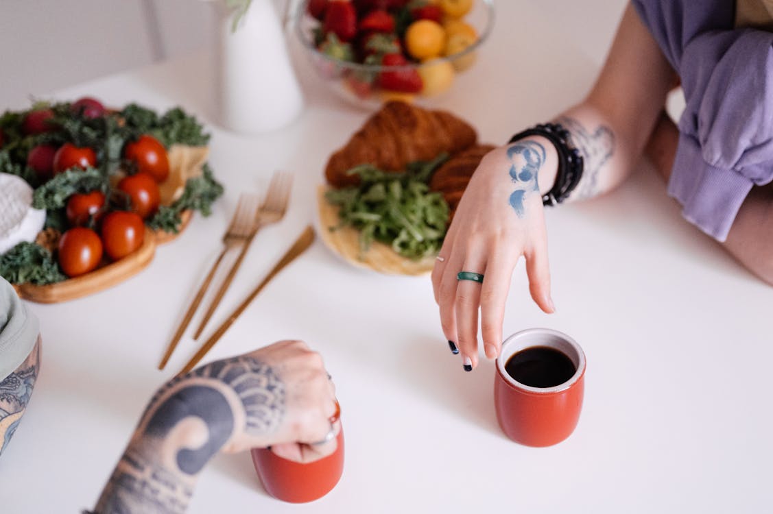 Free Women's Hands Beside Cups at Dinner Table Stock Photo