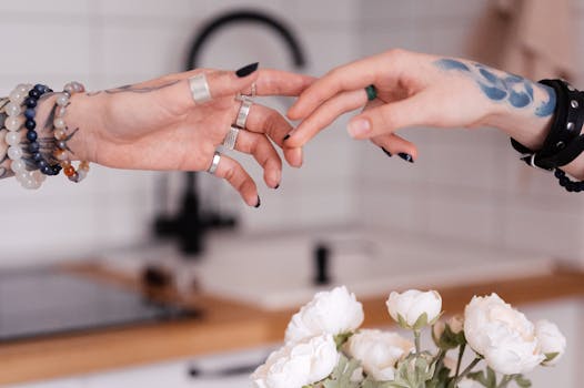 A close-up of tattooed hands with rings and bracelets in a delicate and artistic pose.