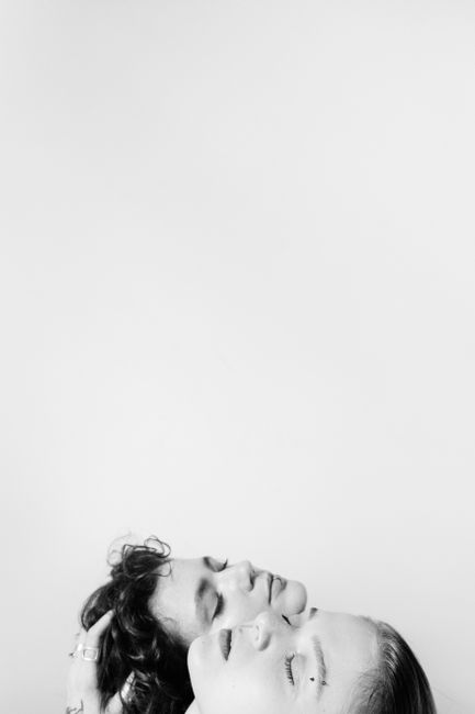 Artistic monochrome portrait of two women with eyes closed, heads touching.