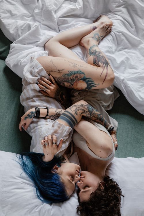 Free A beautiful high-angle view of a tattooed couple embracing on a bed, showcasing love and connection. Stock Photo