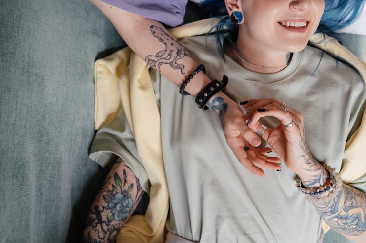 A Tattooed Person In Gray T-shirt Lying On Couch