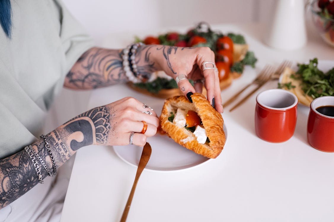 Free Person Holding and Preparing a Croissant Bread on White Plate Stock Photo