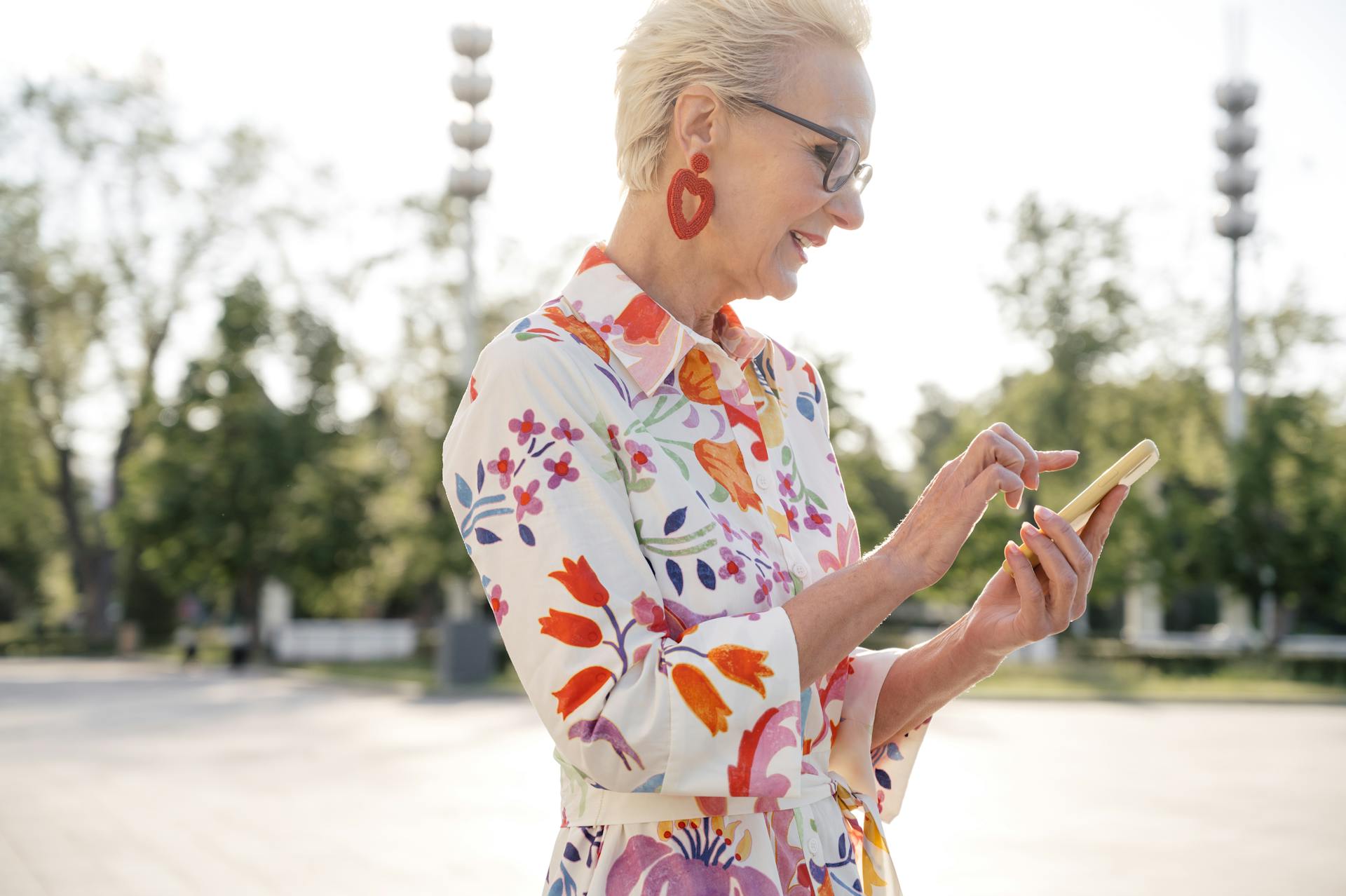 Senior Woman Smiling in Floral Print Dress Using a Mobilephone