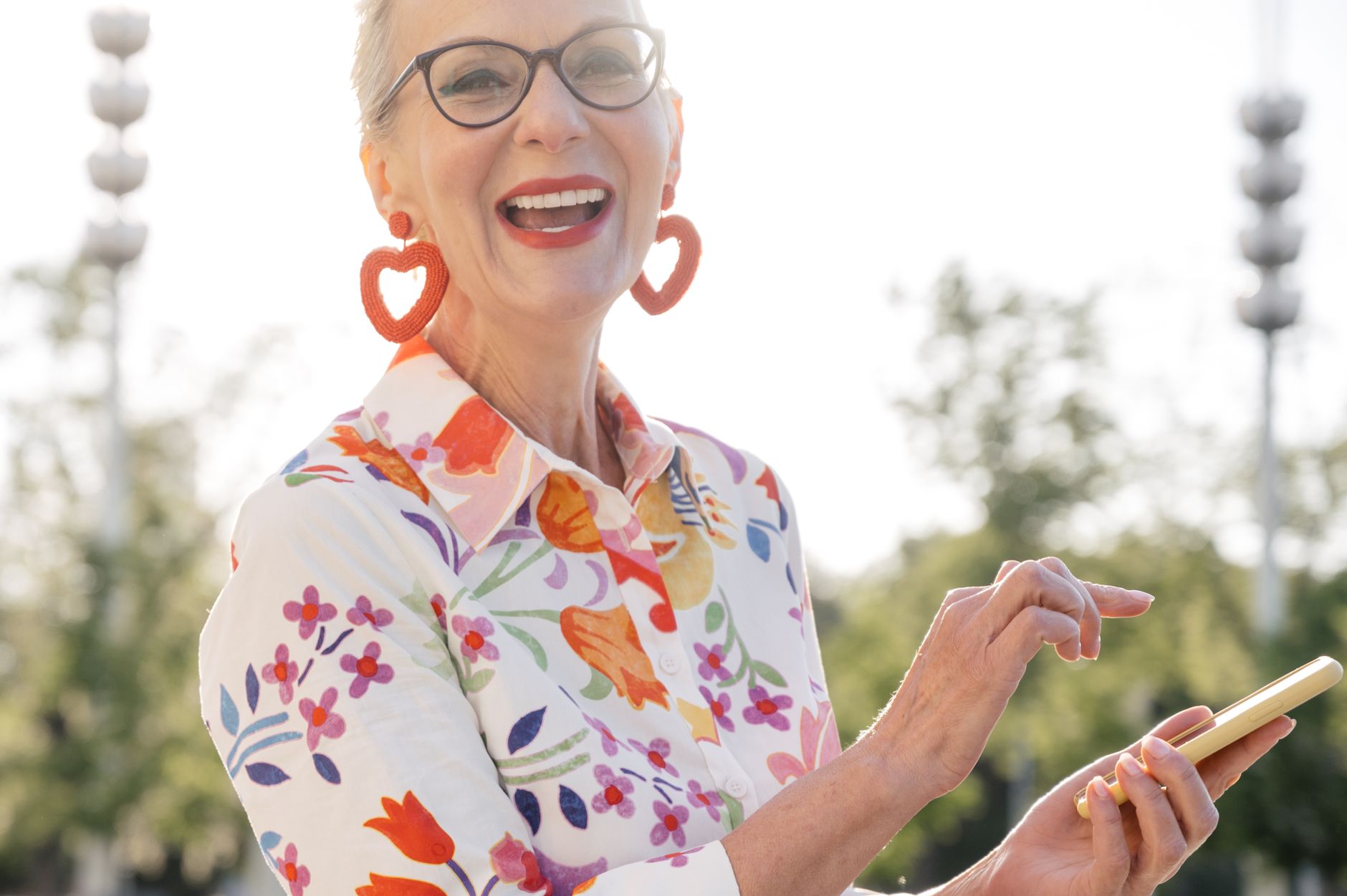 광주 어르신 스마트폰 무료 교육, 동사무소·복지관 신청 정보 한눈에 5 Happy senior woman with glasses, using smartphone and smiling outdoors in a floral shirt.