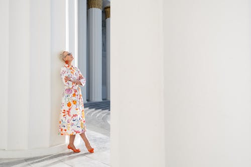 Tourist in a Floral Summer Dress and Orange High Heels Under the Colonnade