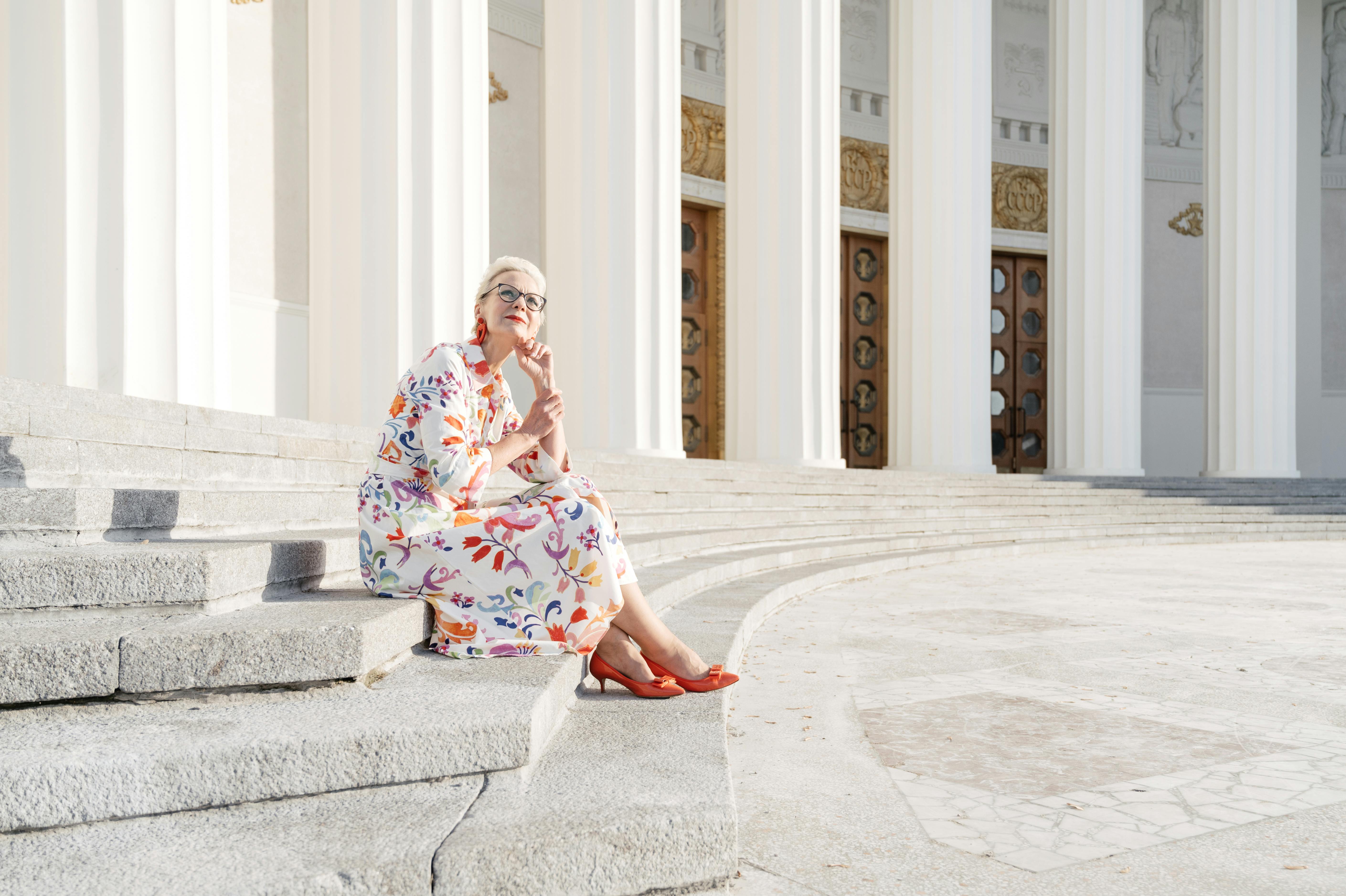 a woman in floral dress sitting on the concrete stairs