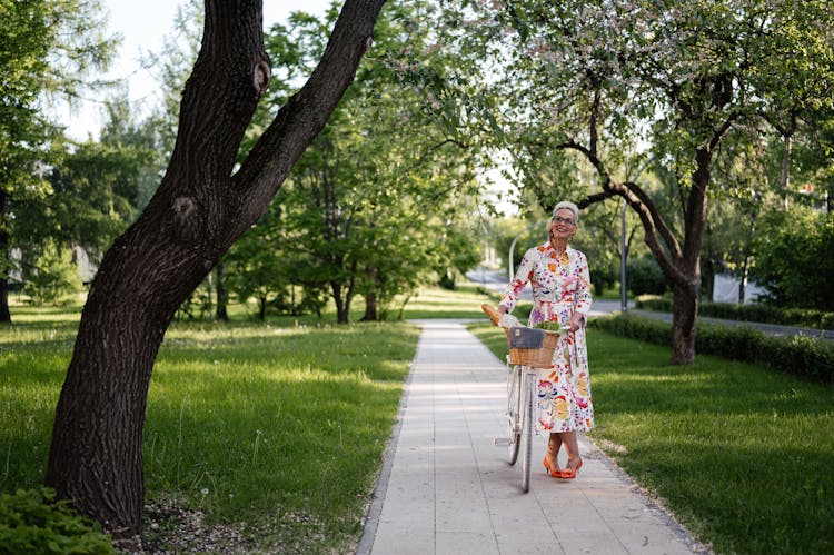 An Elderly Woman With A Bicycle On A Bike Path