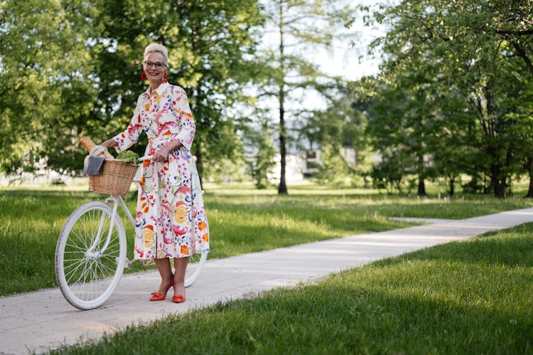 An Elderly Woman With A Bicycle On A Bike Path