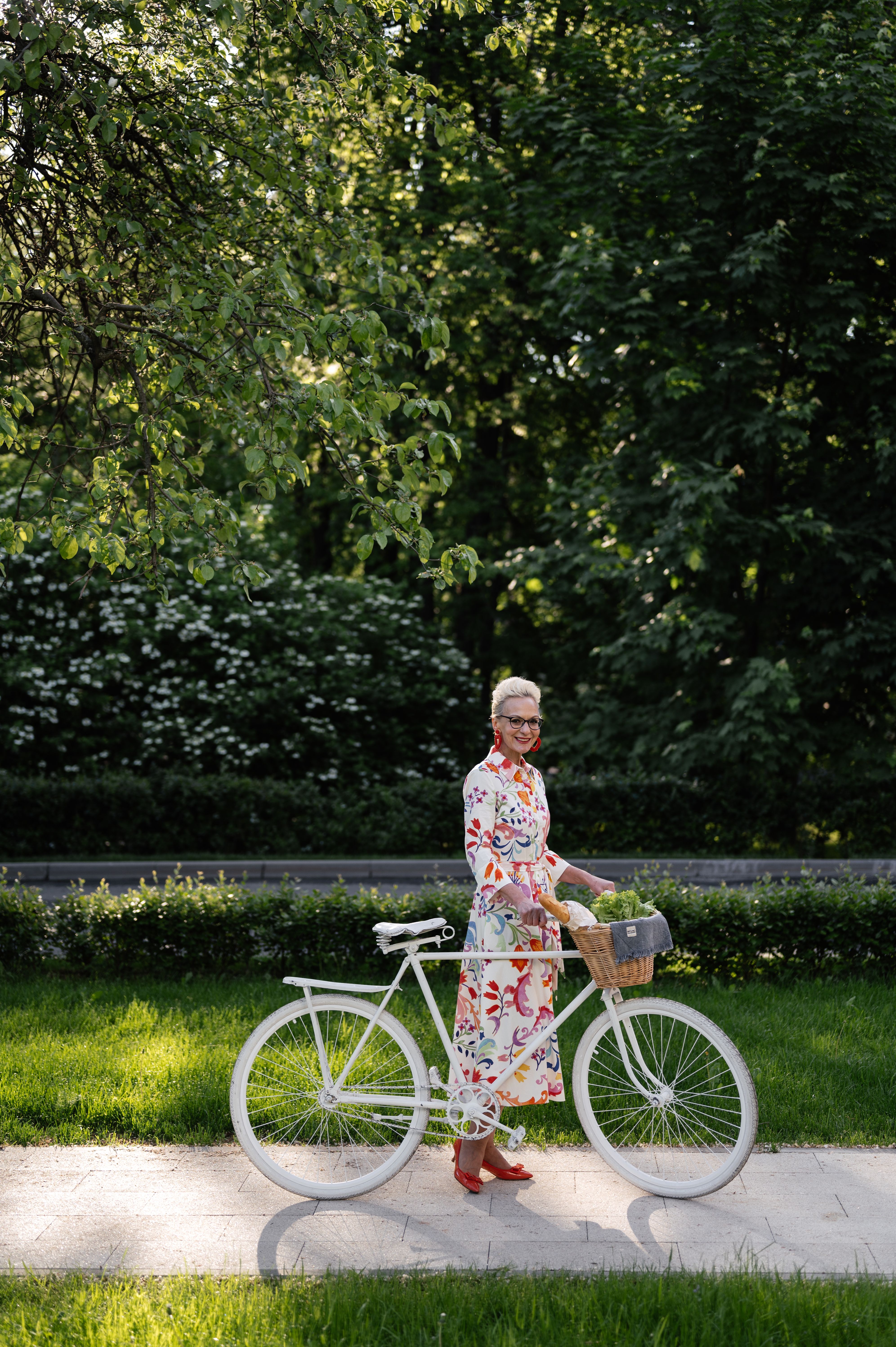 Elderly Woman in Floral Dress Standing Beside a Bicycle · Free Stock Photo