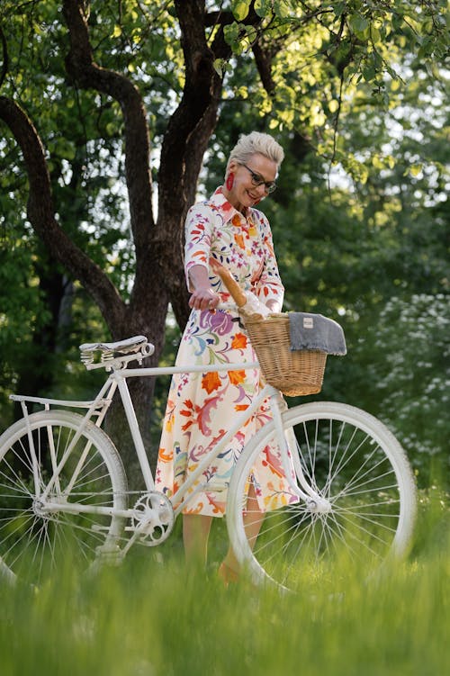 An Elderly Woman in a Printed Dress Holding a Bicycle