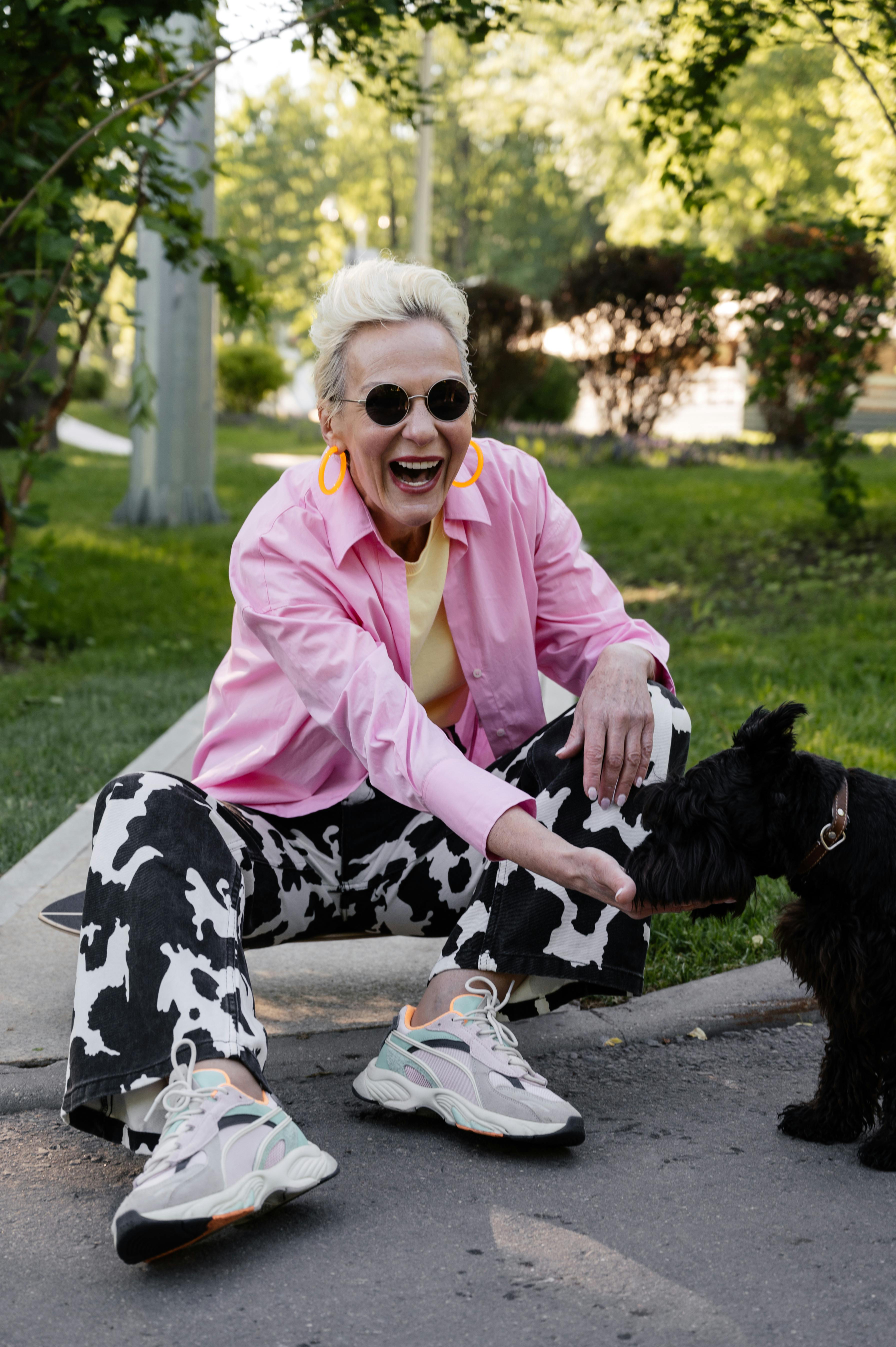 Senior Woman in Pink Long Sleeves Feeding a Dog