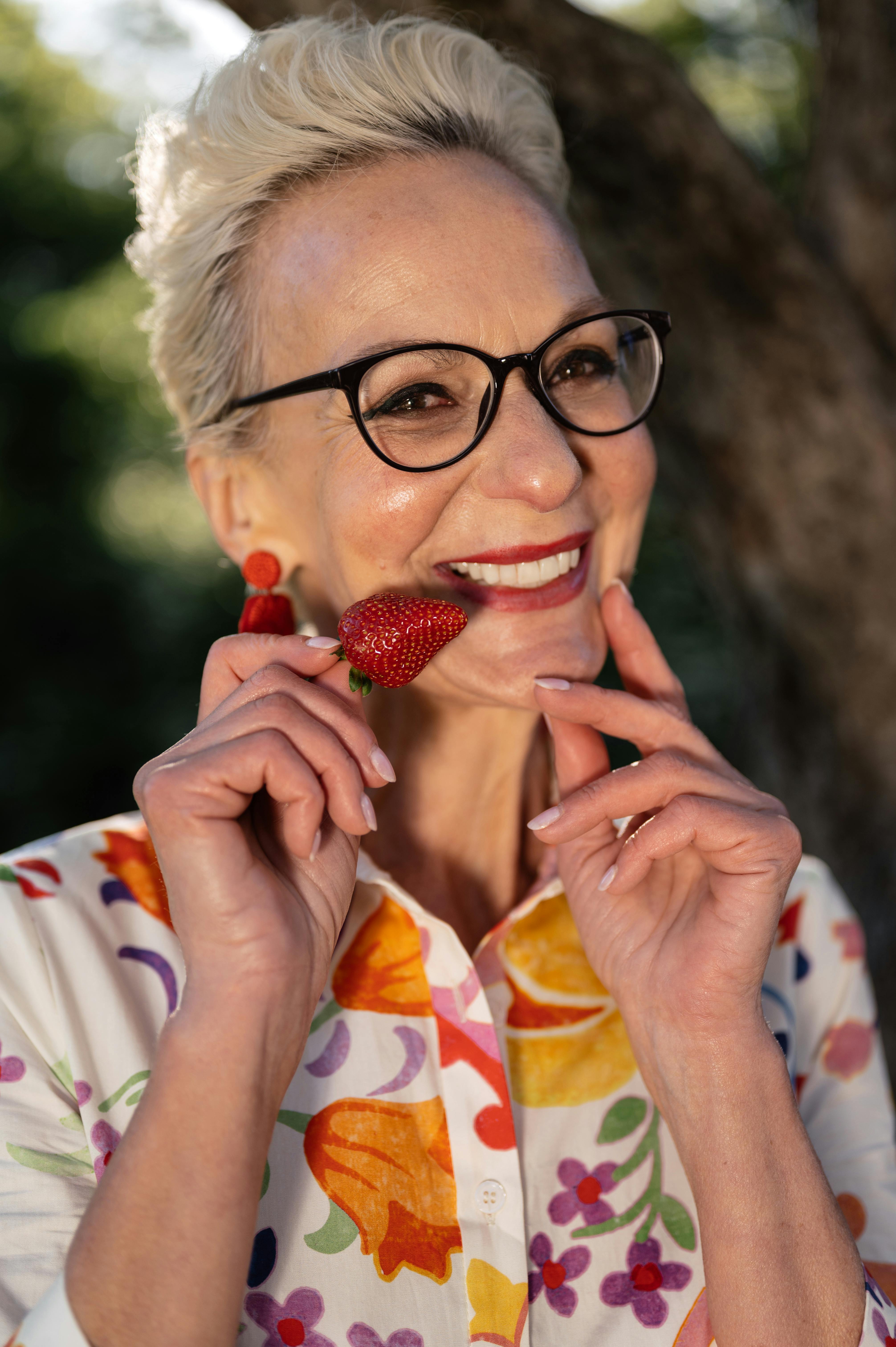 woman in floral shirt holding a strawberry