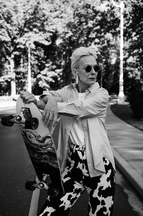 Free Woman Wearing Long Sleeves Holding a Skateboard Stock Photo