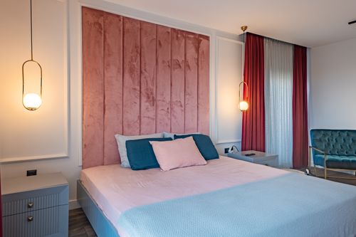 Free Stylish bedroom featuring modern lighting and plush velvet details, creating a cozy home interior feel. Stock Photo