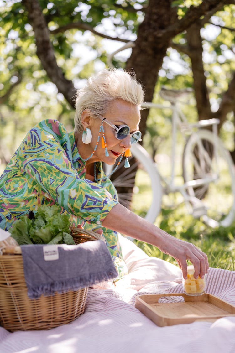 An Elderly Woman Sitting On A Grassy Field