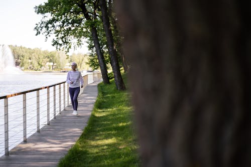 Photograph of an Elderly Woman Jogging Near Trees
