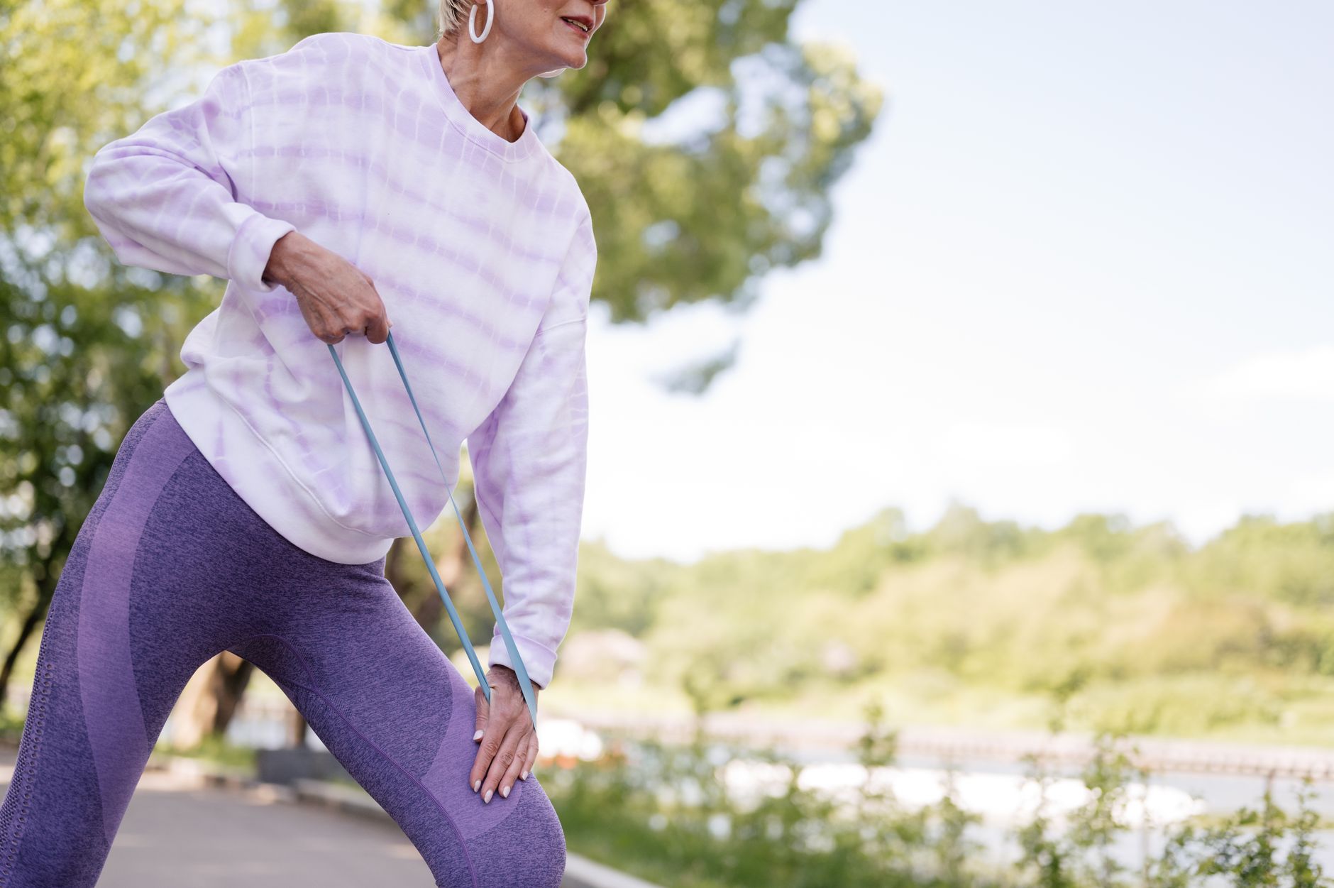A senior woman in activewear exercising outdoors with a resistance band, enjoying a healthy lifestyle.